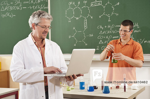Mann mit Laptop und jungem Mann beim Experimentieren im Hintergrund