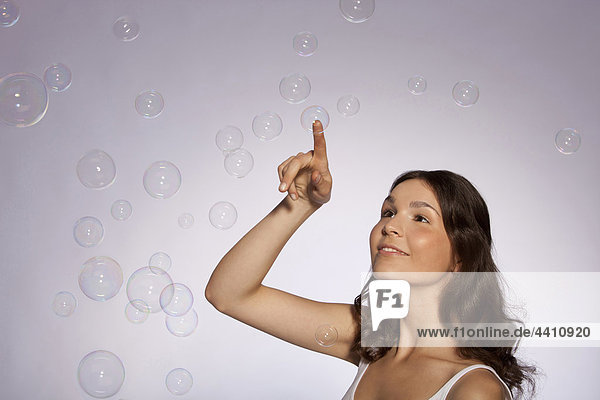 Young woman touching soap bubble  smiling