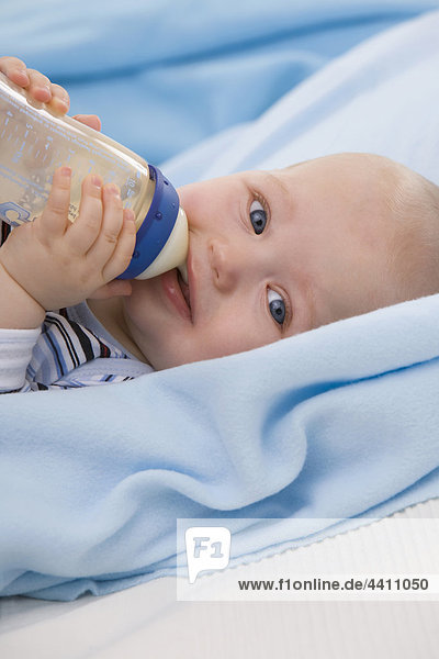 Baby boy (6-11 months) drinking milk  smiling  portrait