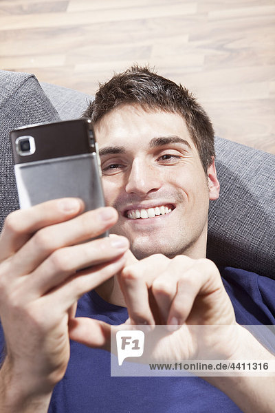 Mann SMS auf dem Handy  lächelnd  Nahaufnahme