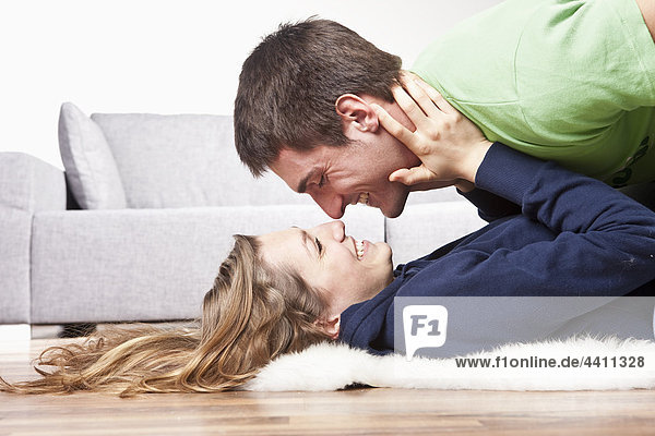 Junges Paar auf dem Boden liegend  Nase reiben  Seitenansicht