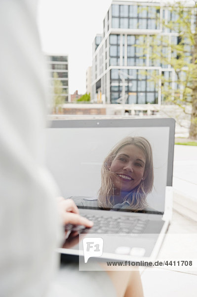 Geschäftsfrau lächelt am Hafen mit Laptop