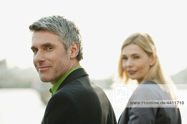 Geschäftsmann lächelnd mit Frau im Hintergrund