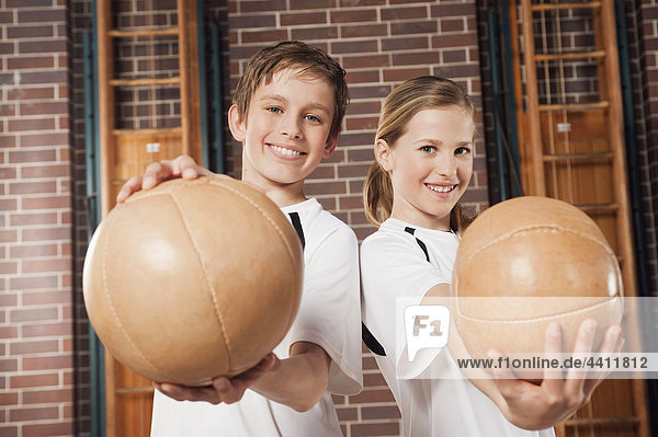 Junge und Mädchen (12-13) halten Ball und Lächeln  Portrait