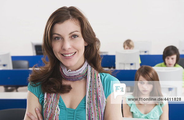 Germany  Emmering  Teacher smiling with students using computer in background