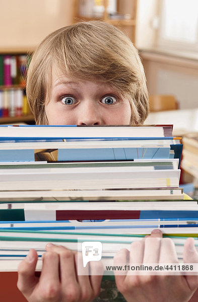 Boy (12-13) holding stack of books  portrait  close up