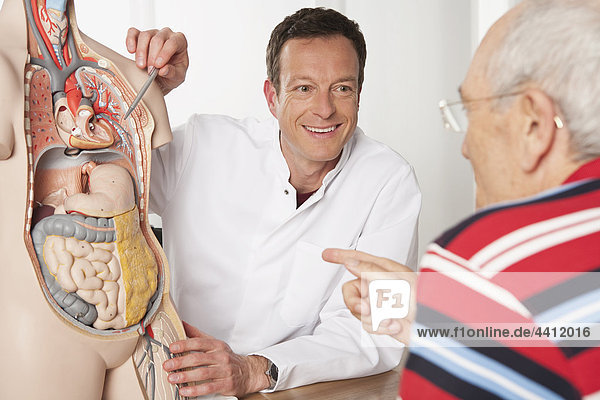 Deutschland  München  Arzt erklärt Patienten den menschlichen Körper  lächelnd