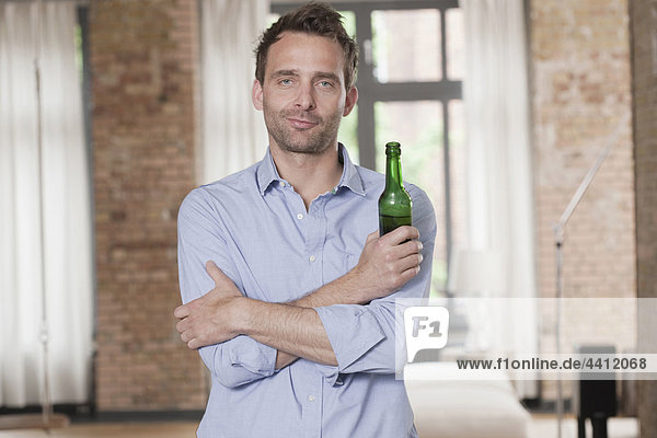 Deutschland  Mann steht und hält Bierflasche  Portrait