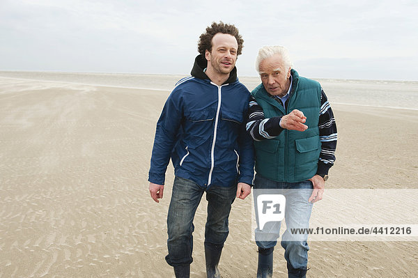 Nordsee  älterer Mann und Sohn  der am Strand spazieren geht.