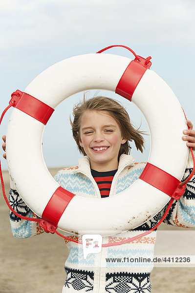 Deutschland  Nordsee  St.Peter-Ording  Junge (8-9) mit Lebensretter am Strand  lächelnd  Portrait