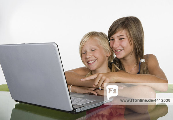Two girls (10-11) using laptop  smiling
