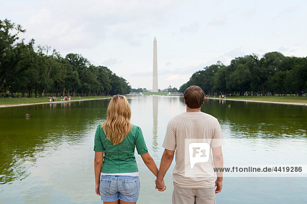 Rückansicht des jungen Paares mit Blick auf das Washingtoner Denkmal