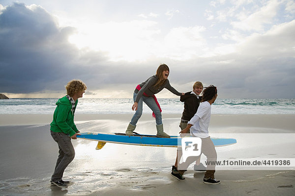 Young people carrying surfboard  person balancing on top