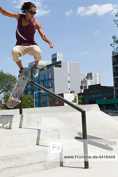 Skateboarder jumping over a rail