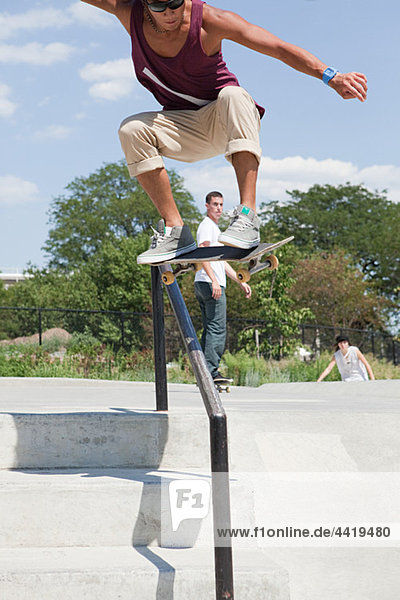 Skateboarder springt über Geländer