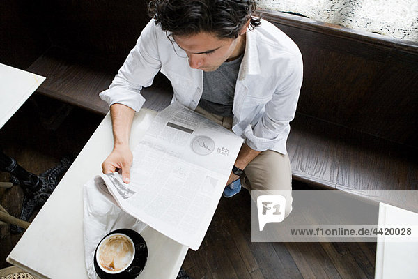 Mann liest Zeitung im Café
