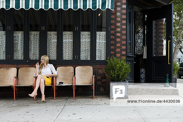 Frau sitzt vor dem Coffee Shop