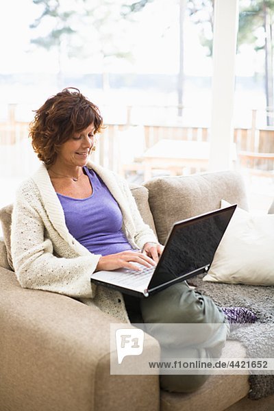 Frau sitzend auf Sofa und Surfen internet
