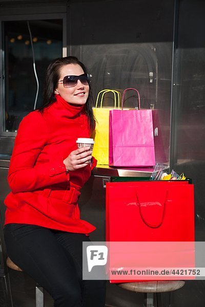 Portrait of junge Frau hält Takeaway Kaffee  mit Einkaufstaschen