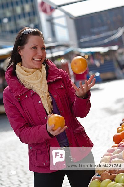 Junge Frau mit frischen Orangen jonglieren
