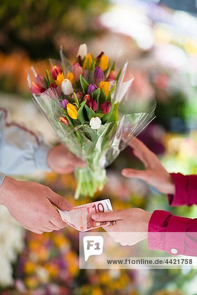 Person buying bunch of flowers from vendor