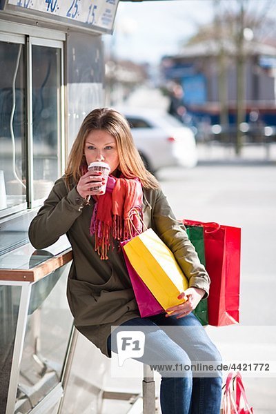 Young woman taking break from shopping  drinking takeaway coffee
