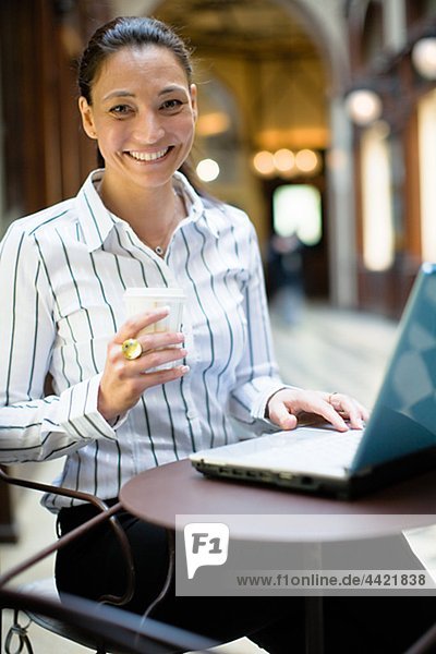 Portrait of mature businesswoman with laptop  holding takeaway coffee
