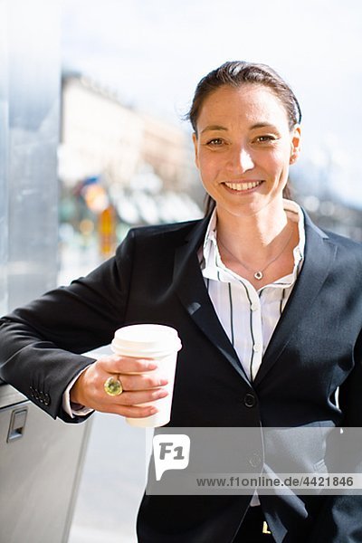 Portrait of cheerful businesswoman with takeaway coffee