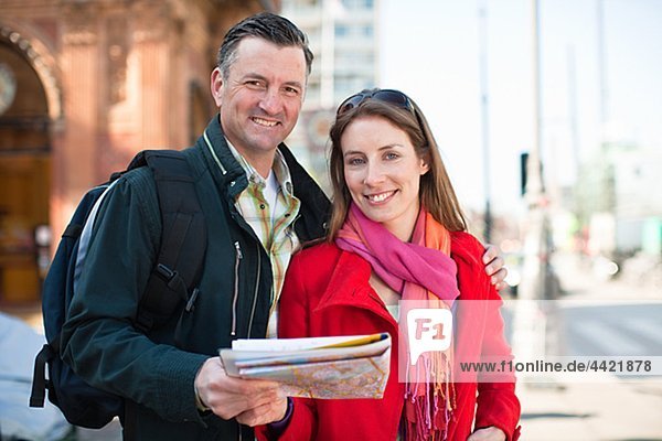 Portrait of couple with map sightseeing in city