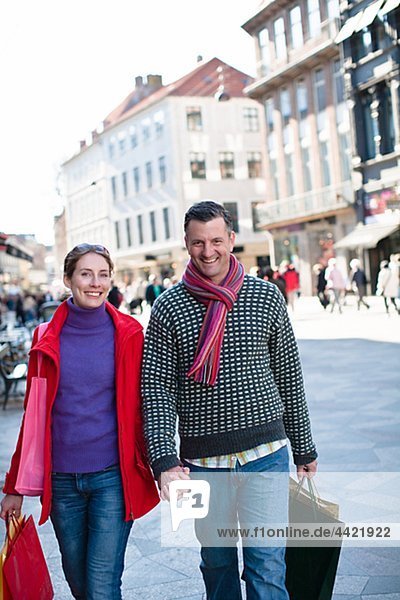 Mid adult couple walking at street with shopping bags