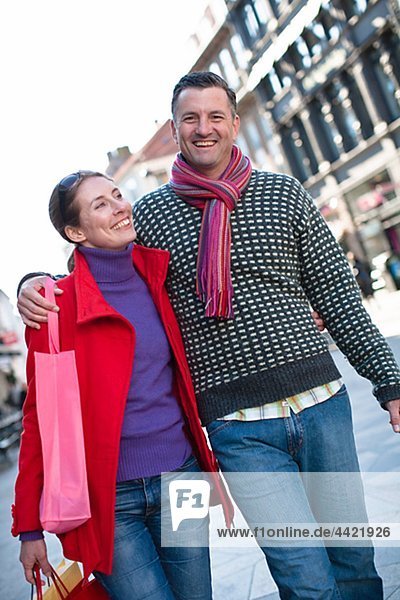 Mid adult couple standing on street with shopping bags