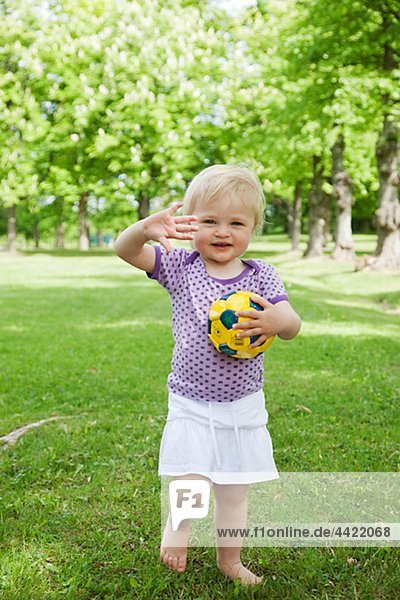 Girl holding ball and waving hands