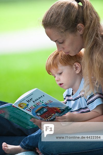 Mid adult women reading book for son