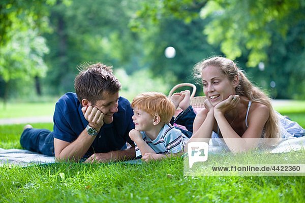 Parents with son lying in park and looking away