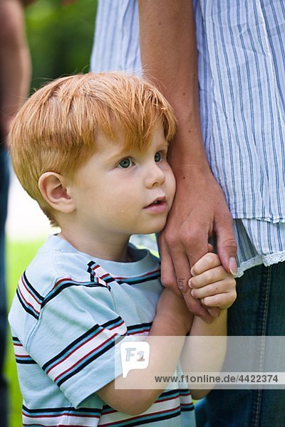 Boy holding mother hand and looking away