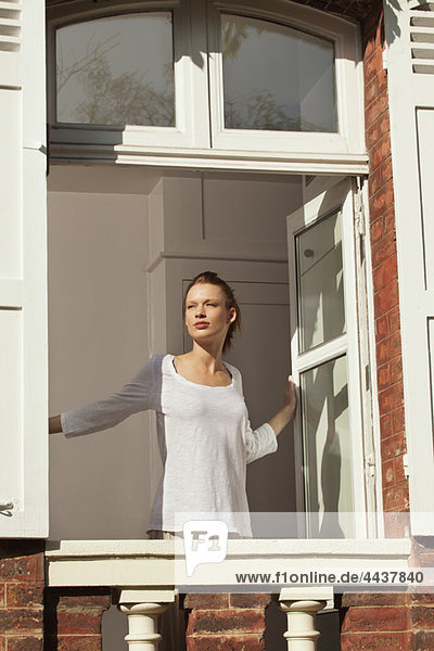 Young woman opening window