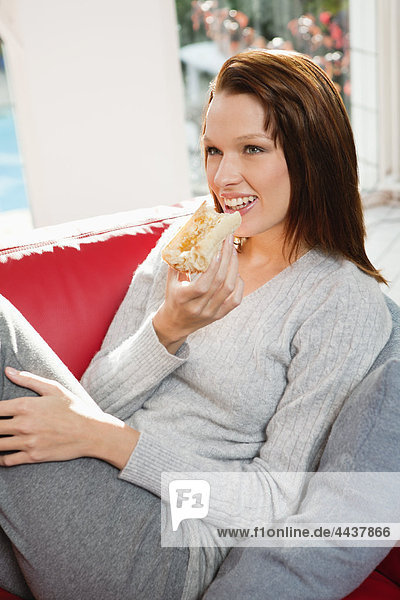 Young woman eating slice of bread