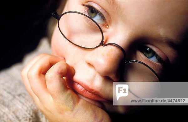child with glasses looking pensive
