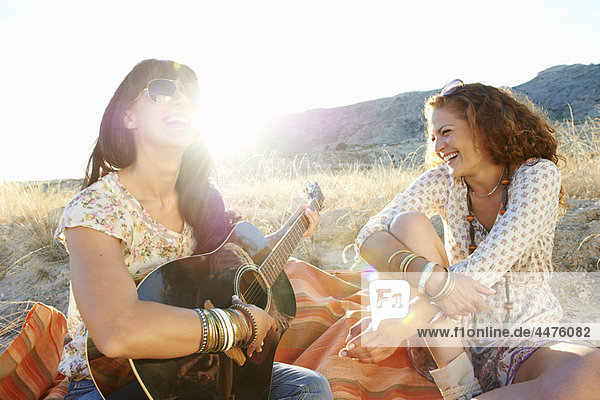 Women playing the guitar in the grass