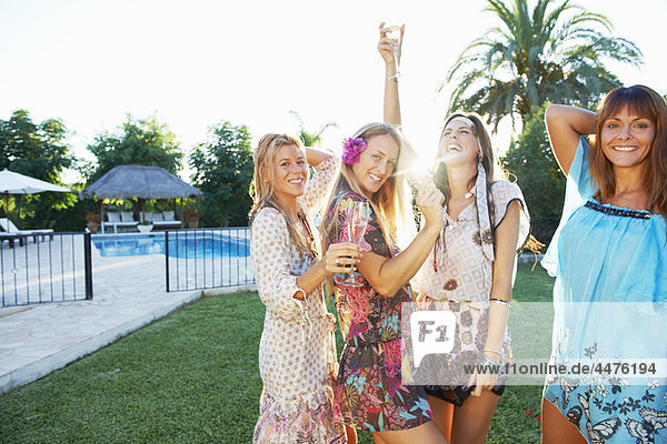 Mädchen feiern mit Getränken am Pool
