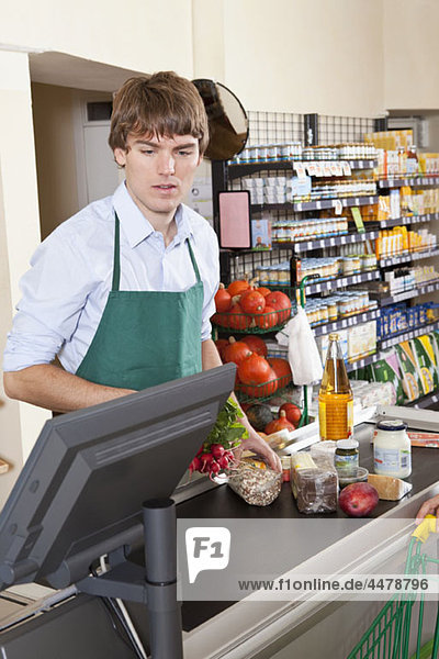 Ein Kassierer  der in einem Supermarkt arbeitet.