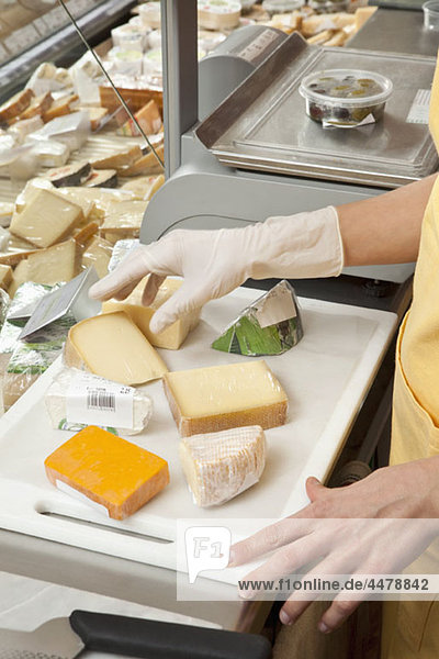 A sales clerk preparing wedges of cheese