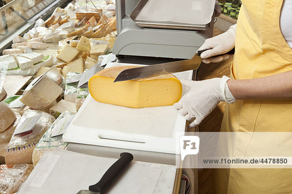 A sales clerk slicing cheese at the cheese counter