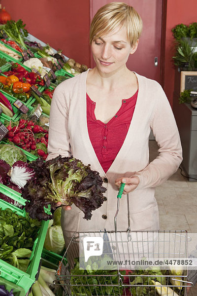 A woman contemplating a head of red leaf lettuce