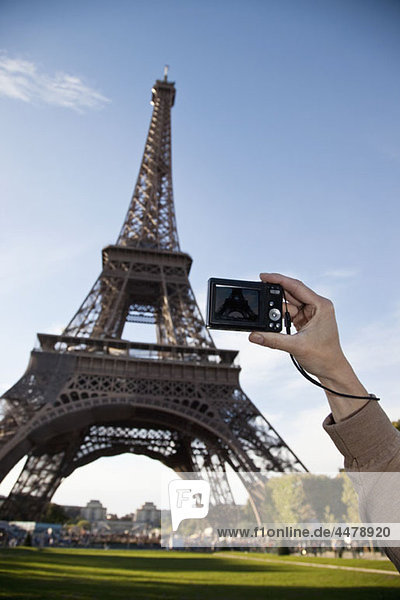 Eine Frau  die den Eiffelturm fotografiert  konzentriert sich auf die Hand.