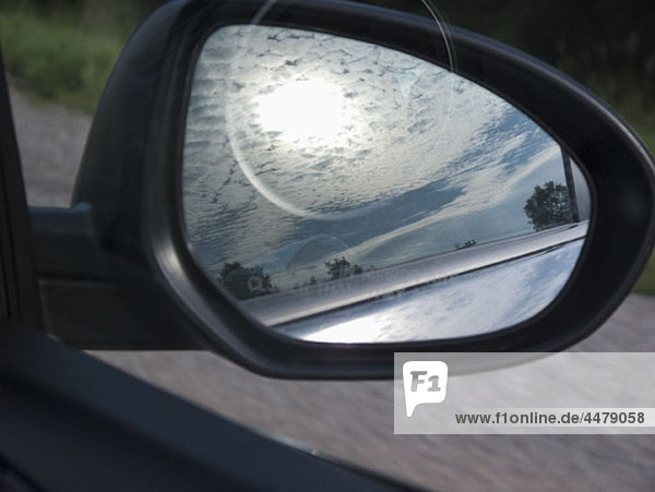 Die Spiegelung des Himmels im Seitenspiegel eines Autos