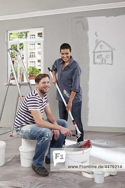 Ein junger Mann und eine junge Frau  die eine Wohnung renovieren.