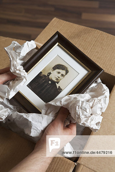 A man holding a picture wrapped in packing paper  focus on hands