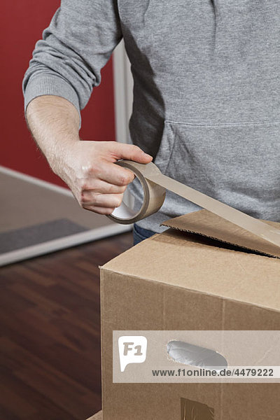 A man taping a moving box shut  midsection