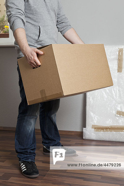 Ein Mann  der eine bewegliche Kiste trägt  mit dem Hals nach unten.